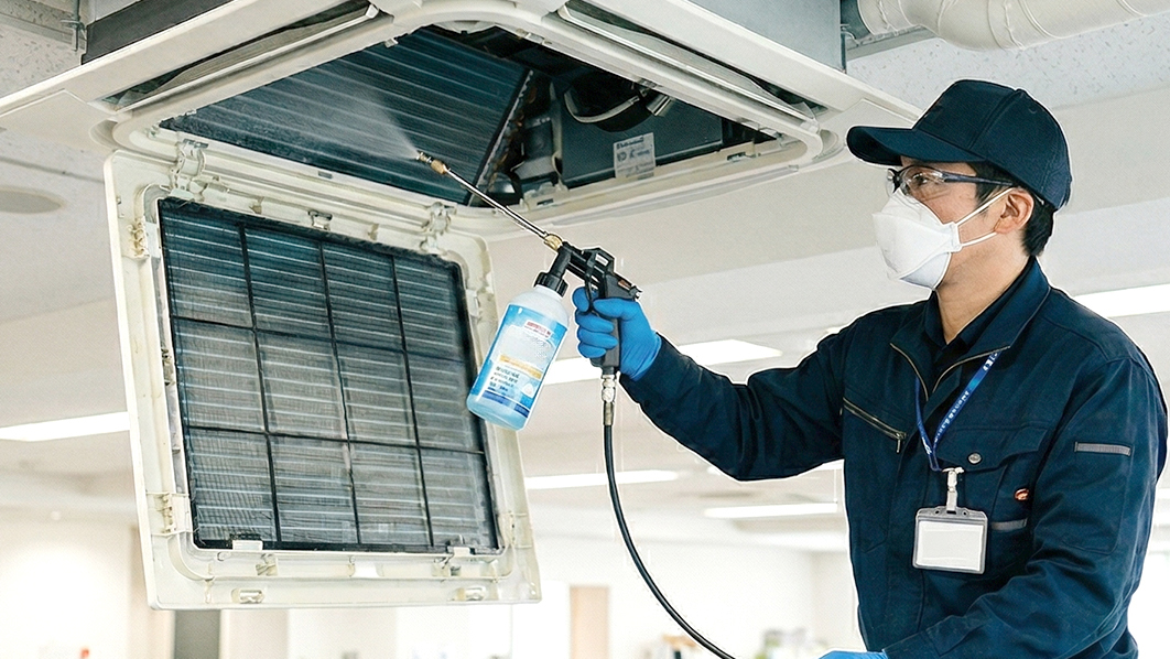 業務用エアコンにコーティング剤をかける男性スタッフ